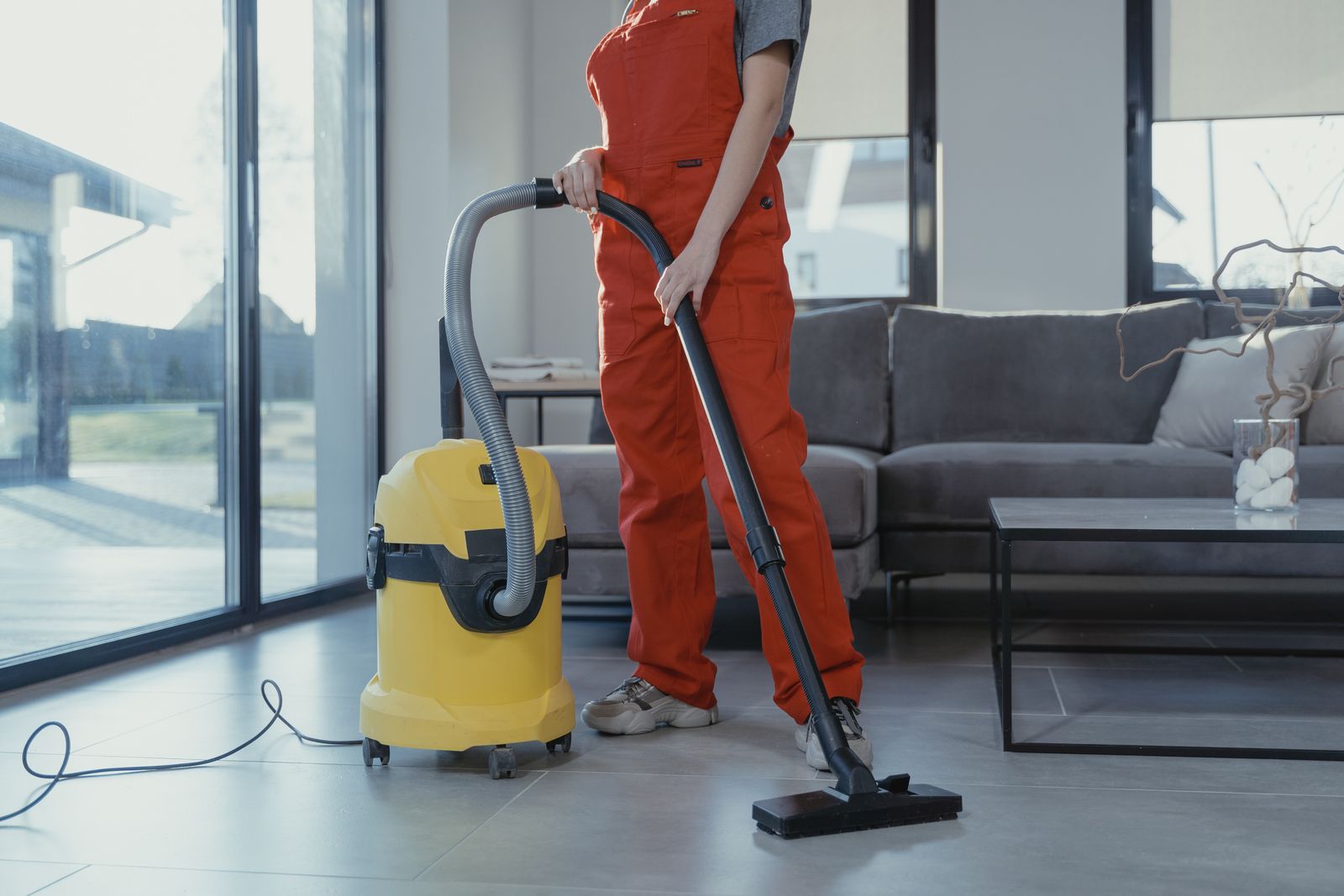 Professional cleaner vacuuming the floor of a bright modern living room